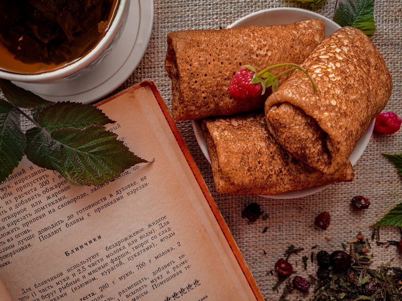 Delicious rustic breakfast scene with pancakes, tea, and a vintage cookbook for cozy mornings.