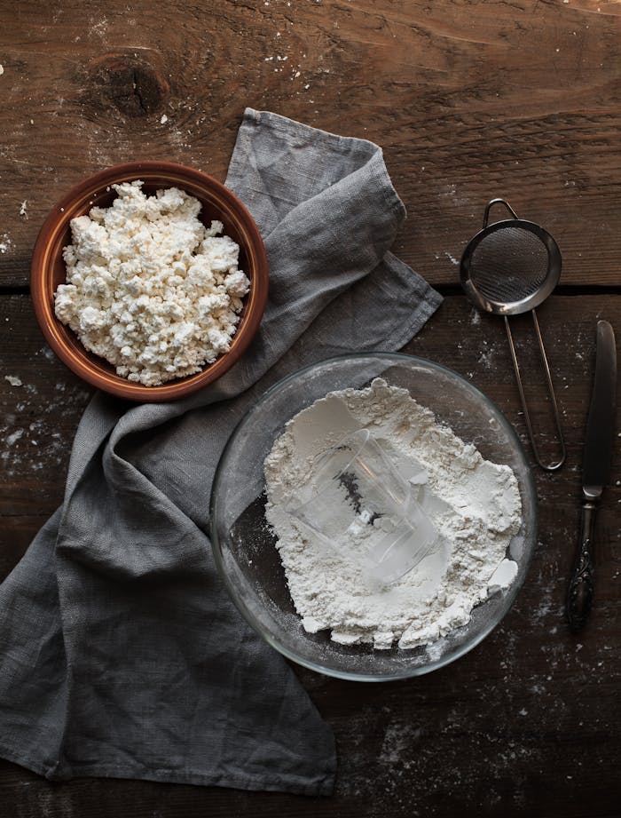 Top view of flour and cottage cheese on a rustic wooden table, perfect for baking inspiration.