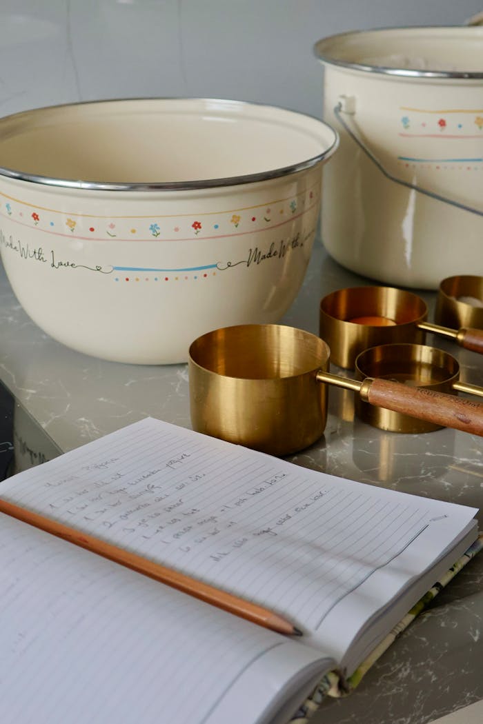Vintage kitchen setting with bowls, brass cups, and a handwritten recipe.